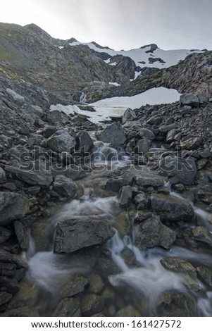 Clear mountain stream forms from summer snow melt from the rugged rocky peak of Bear Mountain on Baranof Island in southeast Alaska