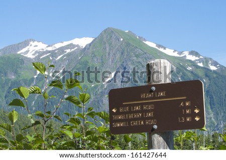 Heart Lake trail marker with snow-capped Bear Mountain in background near Sitka, Alaska on summer day