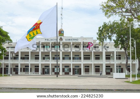 CHETUMAL, MEXICO - OCTOBER 8, 2014: The government palace of Chetumal has had no significant remodeling since 1978.  A large flag of the state of Quintana Roo is in the plaza in front of the palace.