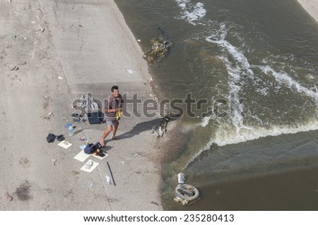 TIJUANA, MEXICO - NOVEMBER 13, 2014: A homeless man dries his clothes as he stands in his boxers and with a bandaged ankle along the heavily contaminated Tijuana River