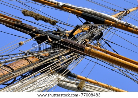 Detail of vintage ship mast with rolled up sail, ropes, pulleys and ladder