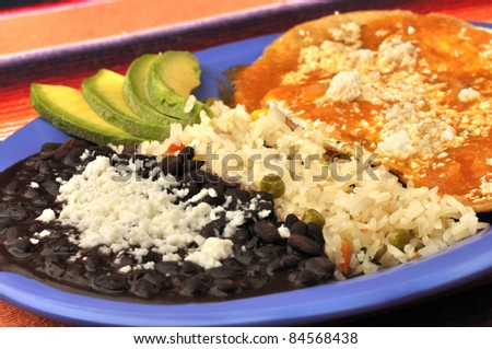 Eggs, tortilla, rice and beans on breakfast plate