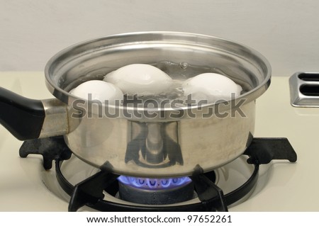 Eggs boiling in pot of water over flame on stove