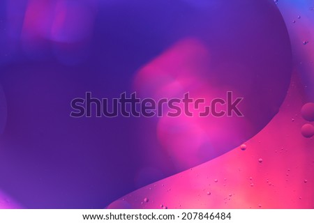 Abstract shapes of pink water forming a wave like a sine-curve in front of a blue blurred background
