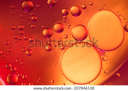Abstract bubbles of water forming like merging cells in front of a blurry background.