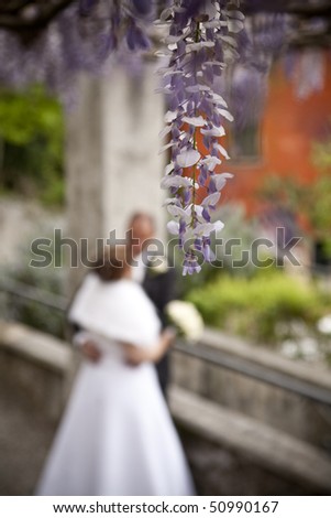 Wedding moments Purple flowers in the foreground with a couple of adults just married, out of focus in the background