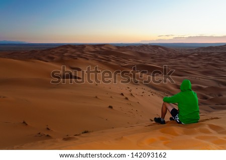 Tourist chilling on the top of sand dune Sahara waiting for sunrise