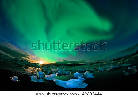 Amazing northern lights performance over glacier lagoon in Iceland during setting moon