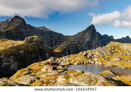 Mountain hut hidden in the heart of Lofoten wild ridge, Norway, Hermannsdalstinden summit in the background