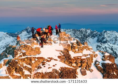 Group of climbers and tourists waiting for amazing sunrise on the summit of Rysy mountain in winter, High Tatras, Slovakia