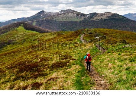 Women hiker is ascending the steep slope with the heavy backpack as the part of the expedition in Bieszczady national park, Poland