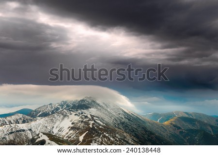 Apocalyptic view on snowy summit of Dumbier peak covered in pillow of clouds in Low Tatras, Slovakia