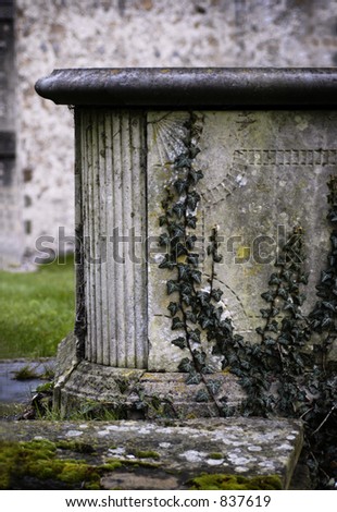A raised tomb half covered in ivy in a European church yard