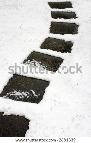 A curving path of square paving stones through a covering of light snow