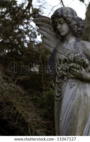 A mossy Victorian era Angel statue in overgrown European Cemetery