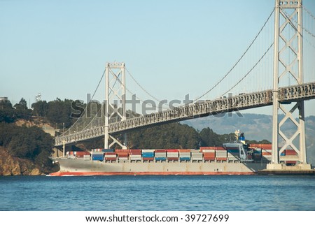A modern container ship sailing from the Port of Oakland to China passes under the San Francisco Bay bridge