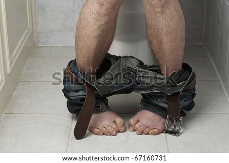Trouble going to the toilet.  Close-up view of male sitting on the toilet seat, feet cringing.