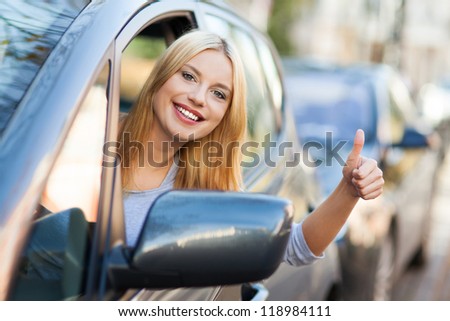 Young woman doing thumps-up in car