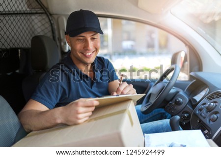 Smiling delivery man sitting with boxes in his van