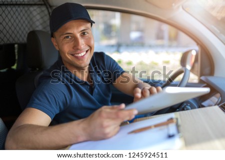 Smiling delivery man sitting with boxes in his van