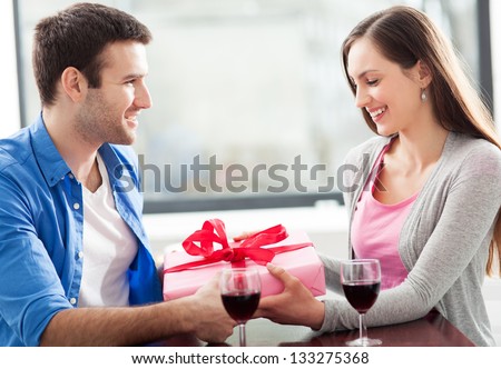 Man giving woman gift at cafe