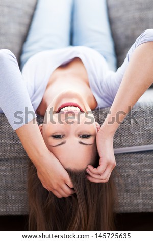 Woman lying upside down on sofa