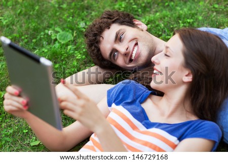 Couple using digital tablet on lawn