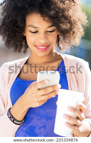 Afro woman with mobile phone and coffee