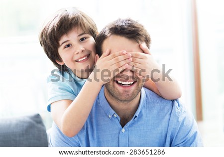 Boy covering father\'s eyes