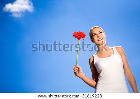 Woman holding flower against blue sky