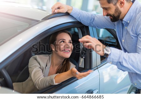 Woman receiving car keys from a dealer