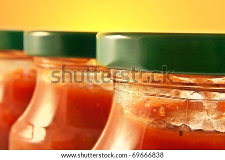 Close up on three pasta sauce jars with yellow background. Focus on foreground jar.