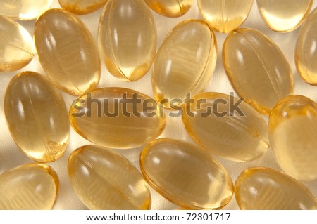 Close up on many cod liver oil capsules arranged on white textile