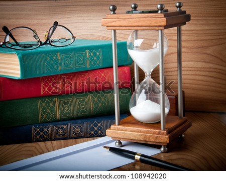 stock photo : Hourglasses and book on a wooden table