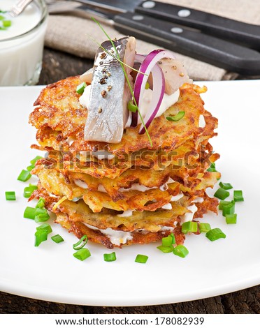 Fried potato pancakes  with herring on the old wooden background