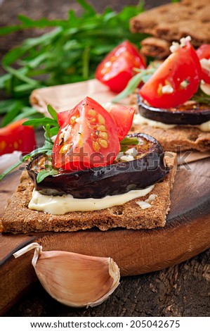 Vegetarian Diet Crispbread sandwiches with garlic cream cheese, roasted eggplant, arugula and cherry tomatoes on old wooden background