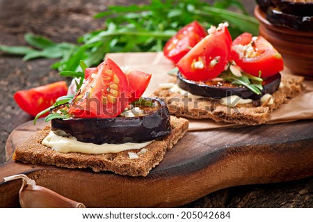 Vegetarian Diet Crispbread sandwiches with garlic cream cheese, roasted eggplant, arugula and cherry tomatoes on old wooden background