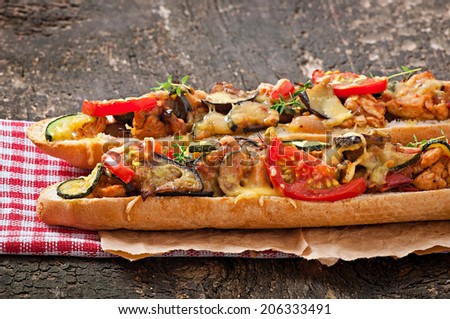 Big sandwich with roasted vegetables (zucchini, eggplant, tomatoes) with cheese and thyme on old wooden background