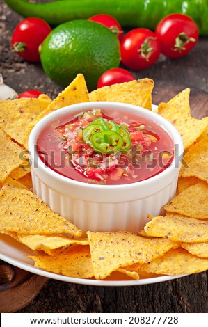Mexican nacho chips and salsa dip in  bowl on  wooden background