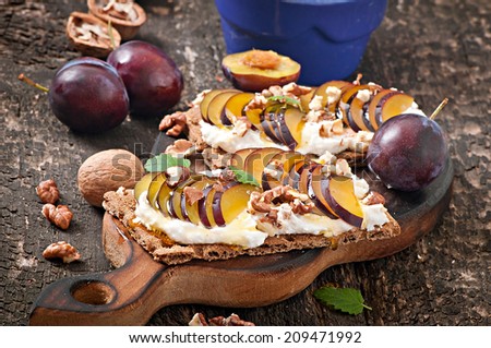 Vegetarian Diet sandwiches Crispbread with cottage cheese, plums, nuts and honey on old wooden background