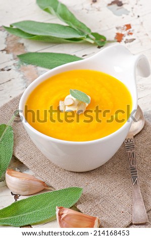 Cream of pumpkin soup with sour cream sauce decorated with a leaf of sage