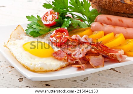 English breakfast - fried eggs, bacon, sausages and toasted rye bread