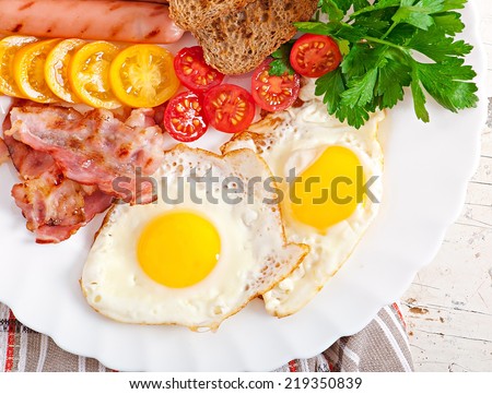 English breakfast - fried eggs, bacon, sausages and toasted rye bread