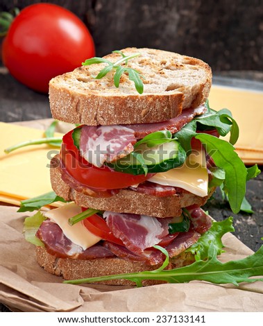 Sandwich with ham, cheese and fresh vegetables on wooden background