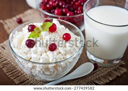 Cheese, milk and cranberries on a wooden table in a rustic style