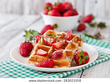 Belgium waffles with strawberries and mint on white plate