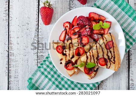 Pancakes with strawberries and chocolate decorated with mint leaf. Top view