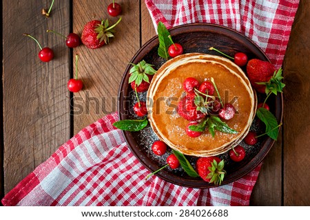 Pancakes with berries and syrup in a rustic style. Top view