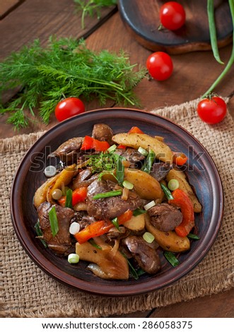 Roast chicken liver with vegetables on wooden background. Top view