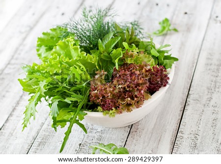 Variety fresh organic herbs (lettuce, arugula, dill, mint, red lettuce) on wooden background in rustic style